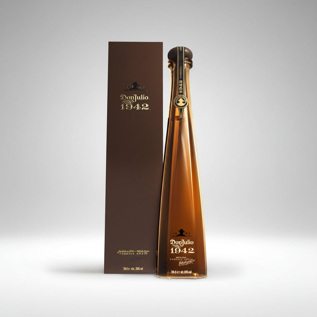A bottle of Don Julio 1942 tequila next to its tall brown packaging box, photographed on a clean white background.