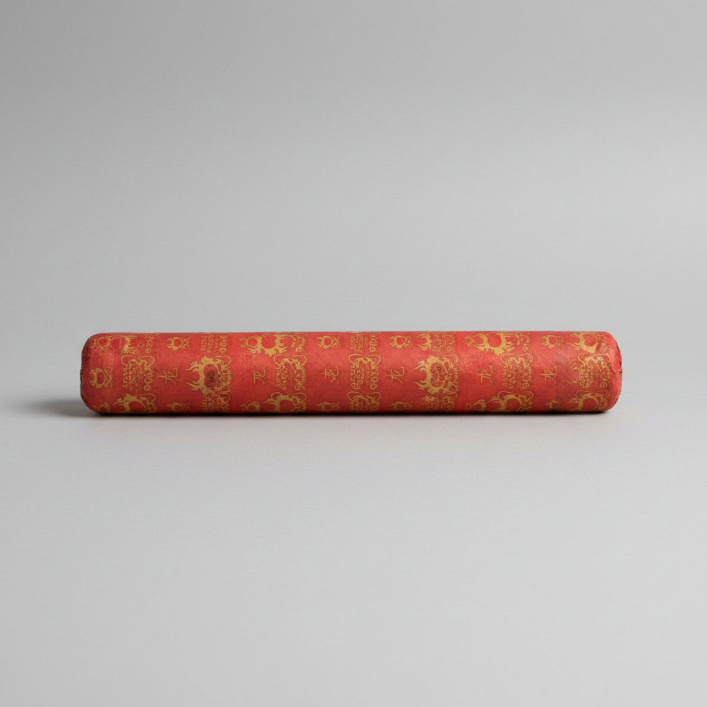 A red cylindrical product, likely a roll of decorative fabric, ribbon, or paper, featuring a repeating gold pattern of Chinese characters and ornamental motifs.