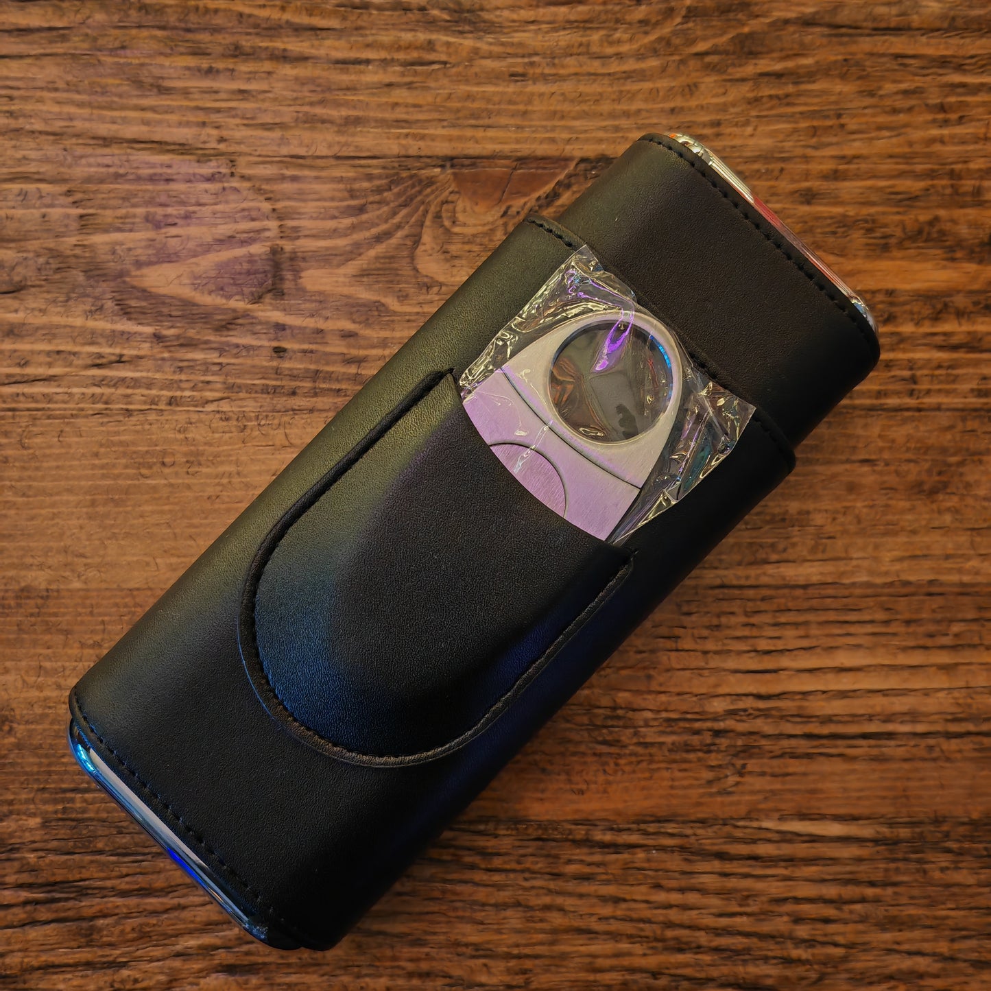 Black cigar case with a cigar cutter on a wooden surface