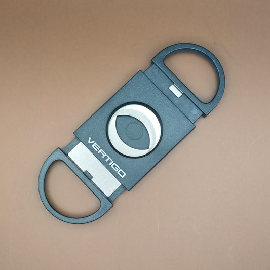 Black cigar cutter with 'VERTIGO' branding on a beige background