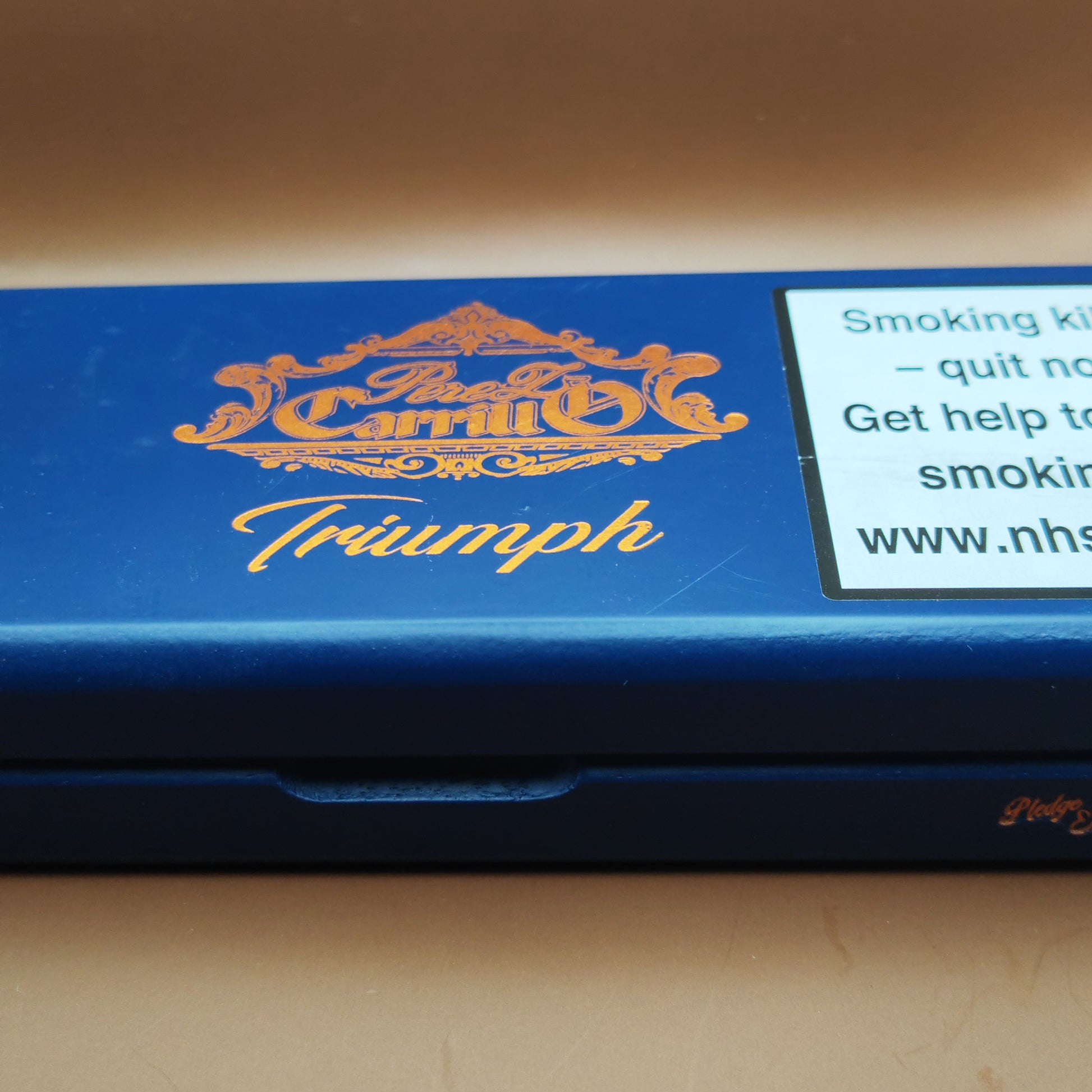 Blue cigarette pack with 'Triumph' branding on a beige background