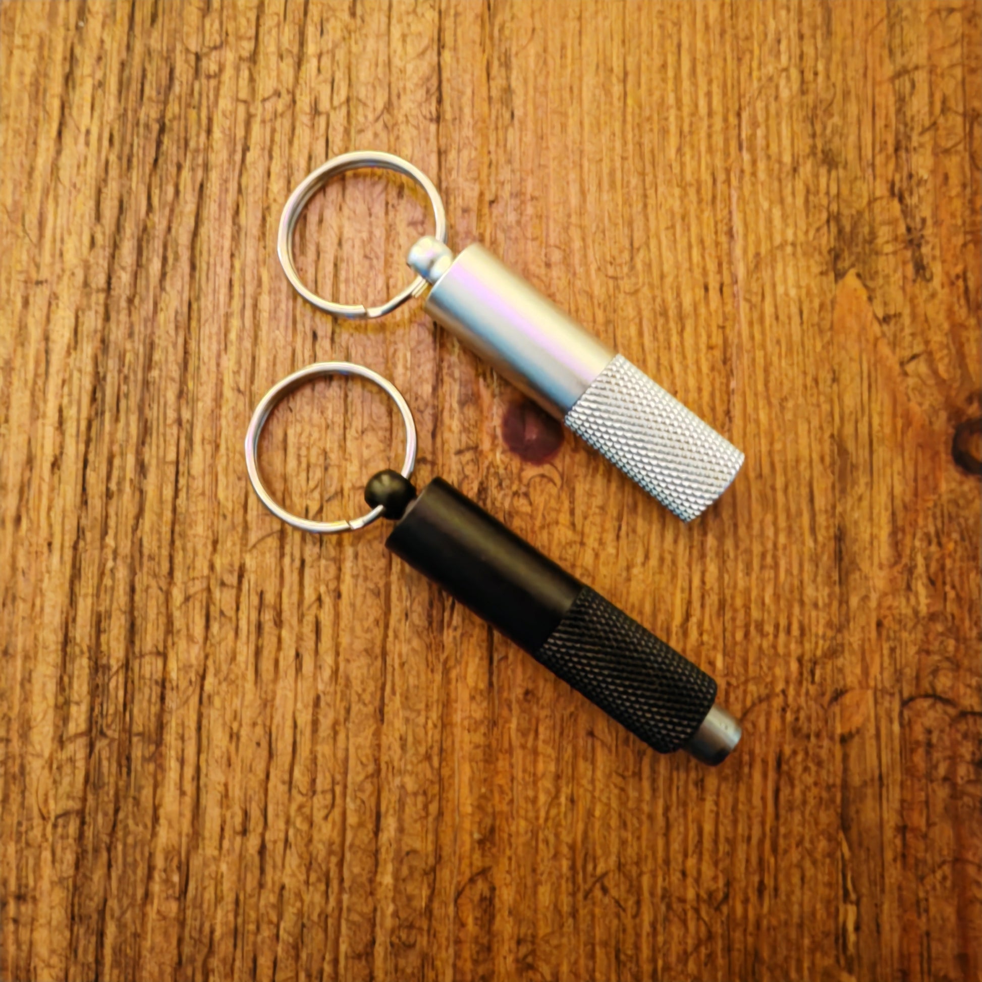 Two keychain cigar punch tools on a wooden surface