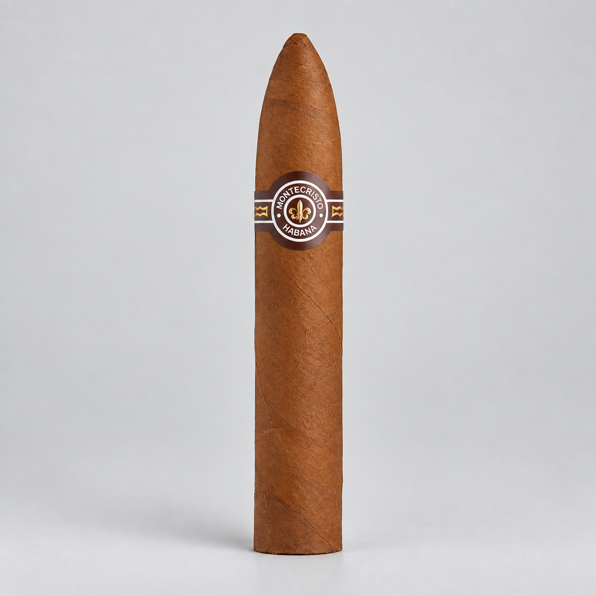 A single brown cigar standing upright on a light gray background, featuring a circular band with the brand name 'Cigarrito de la Mano' and a gold anchor emblem.