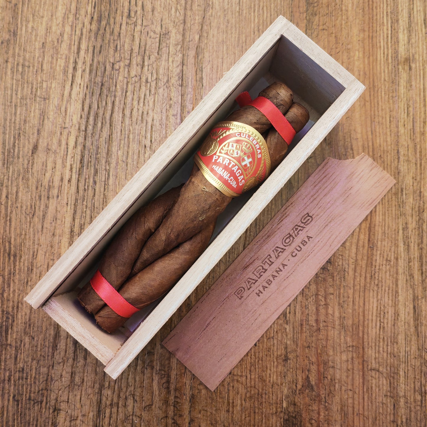 Partagás cigars in a wooden box on a wooden surface