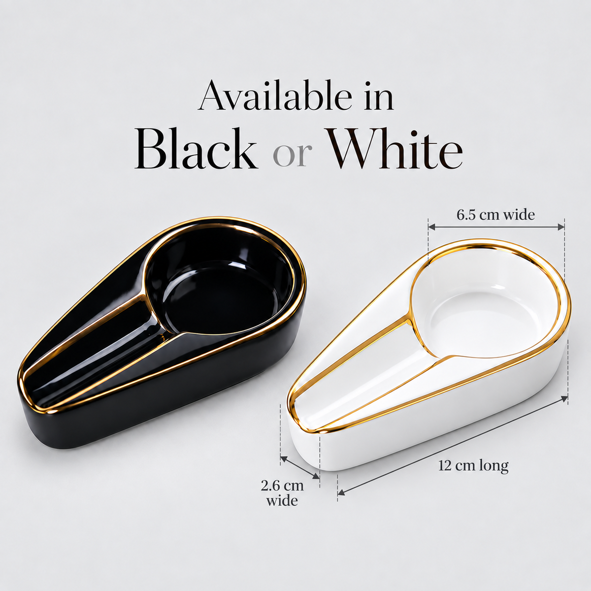 Two elongated ceramic bowls or dish holders shown on a light gray background, one black with gold trim and one white with gold trim. Text above reads 'Available in Black or White,' and dimension callouts indicate 12 cm long, 6.