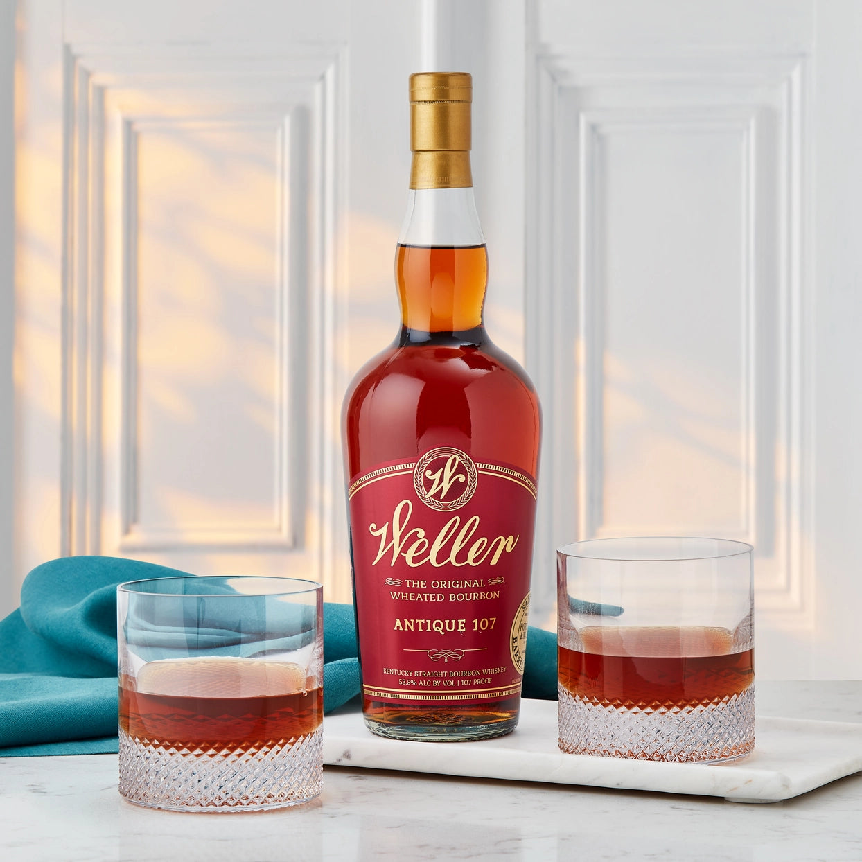 Weller whiskey bottle with two glasses on a marble surface