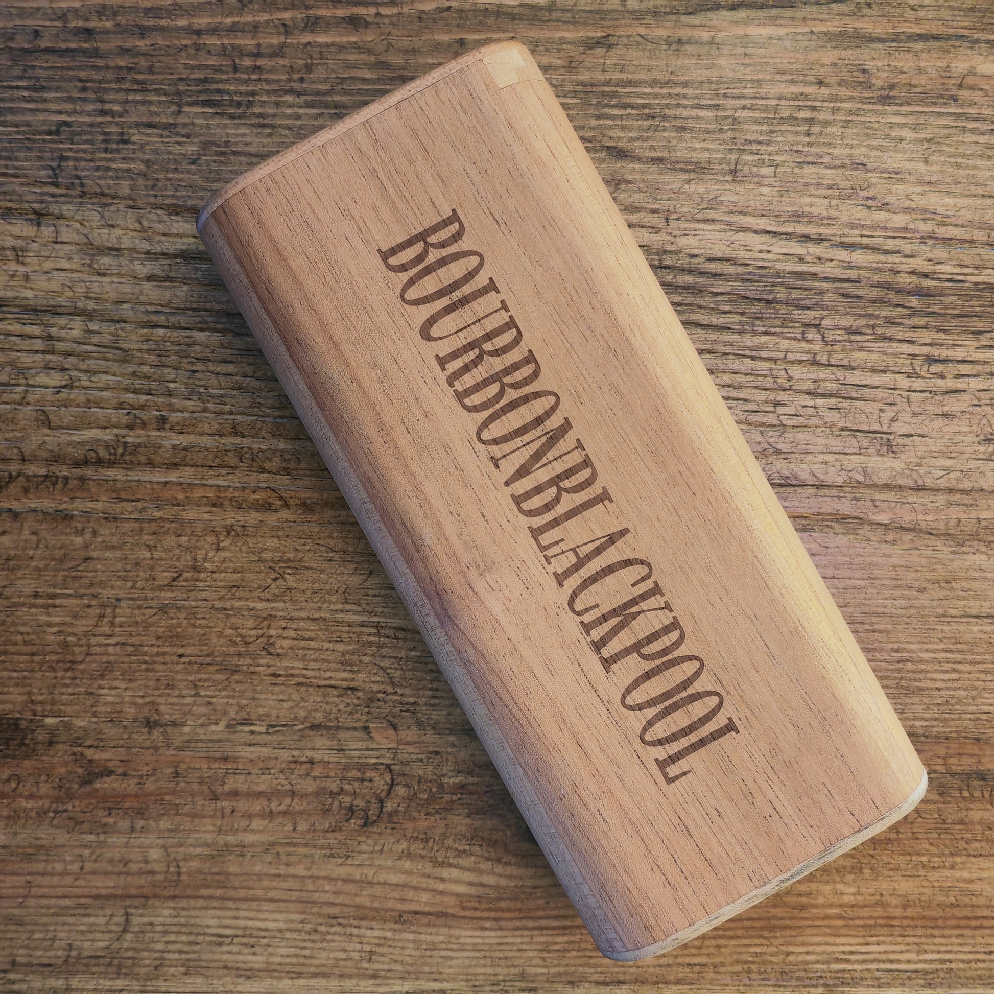 Wooden cigar case with 'Bourbon Blackpool' engraving on a wooden surface
