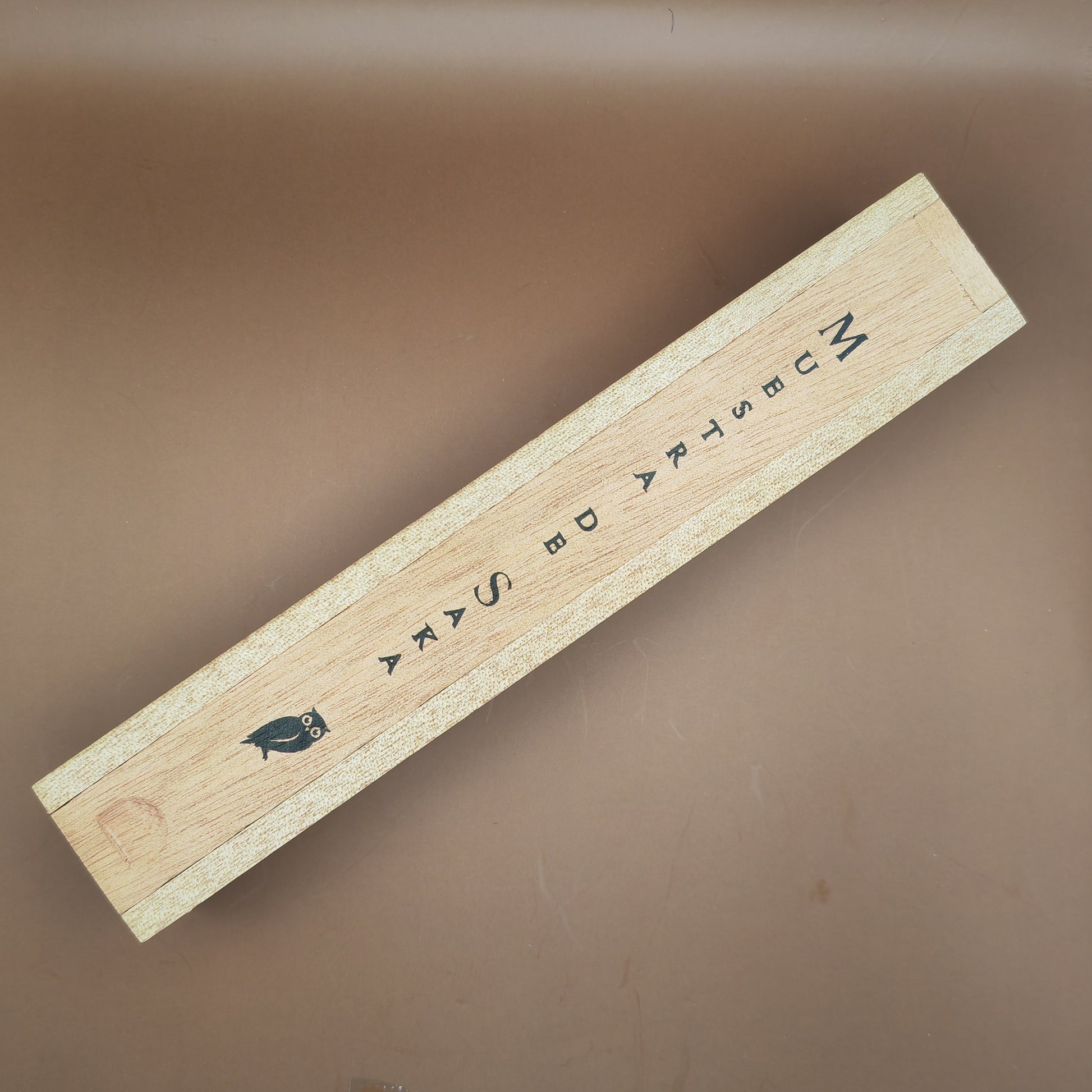 Wooden box with text and a bird illustration on a brown background