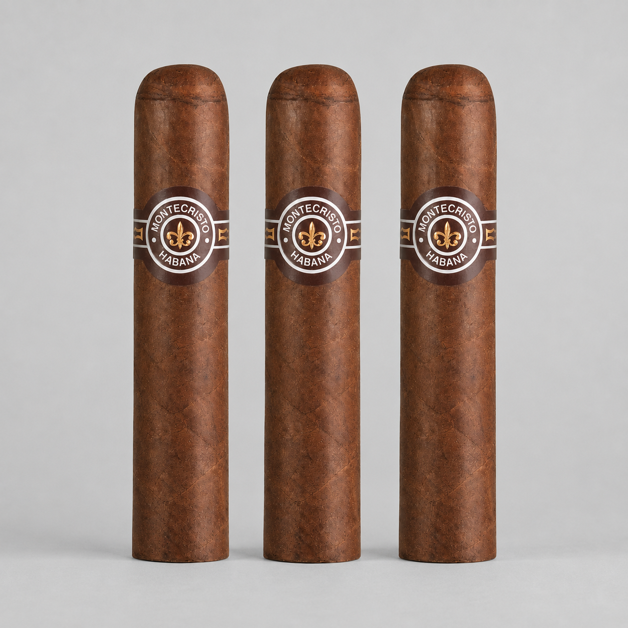 Three Montecristo Haban cigars standing upright in a row against a light gray background. Each cigar has a dark brown wrapper with a circular band featuring the Montecristo logo and the word 'HABAN'.