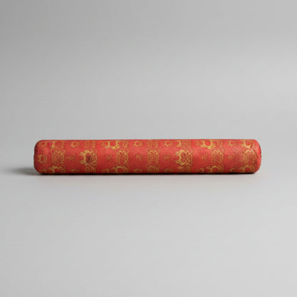 A red cylindrical product, likely a roll of decorative fabric, ribbon, or paper, featuring a repeating gold pattern of Chinese characters and ornamental motifs.