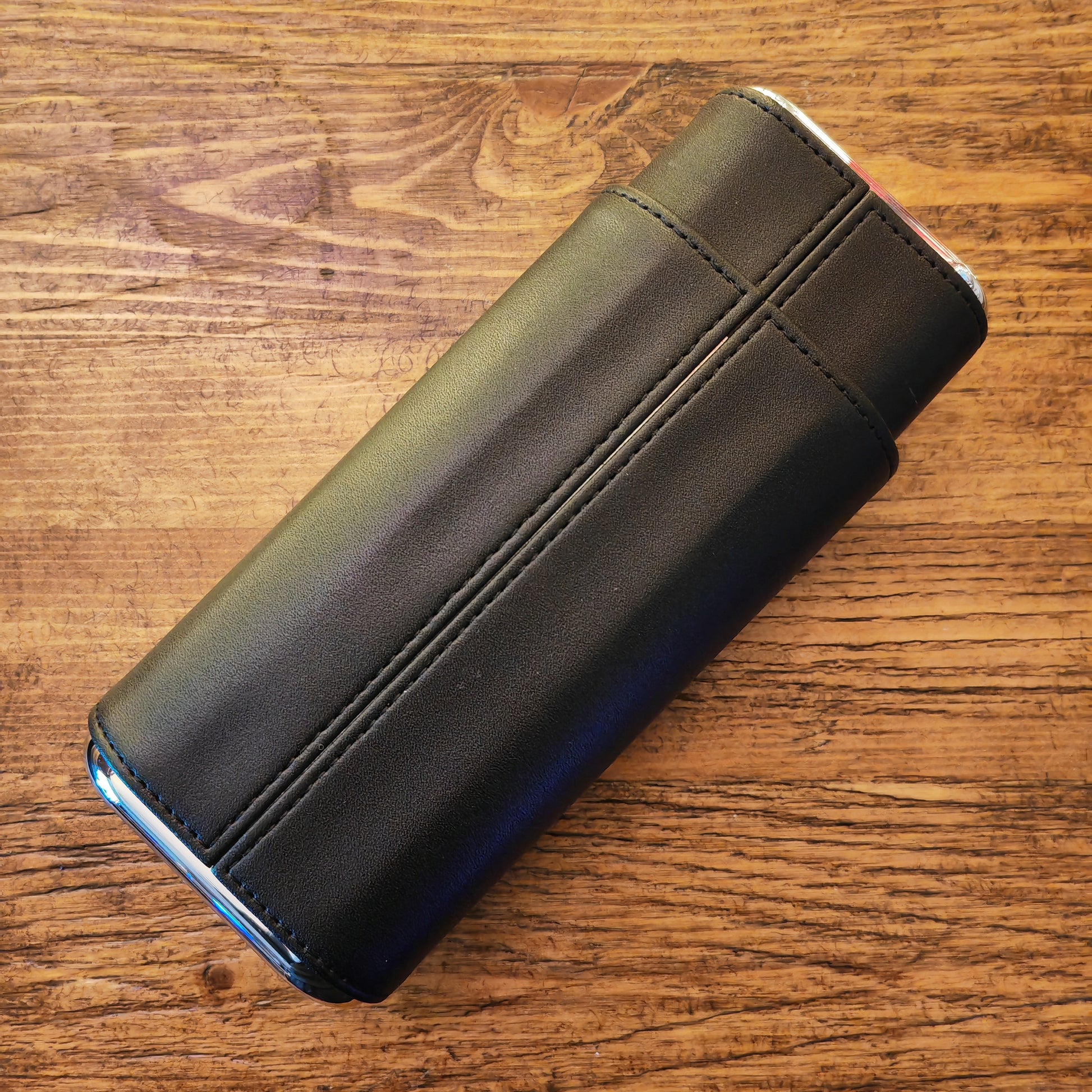 Black leather cigar wallet on a wooden surface