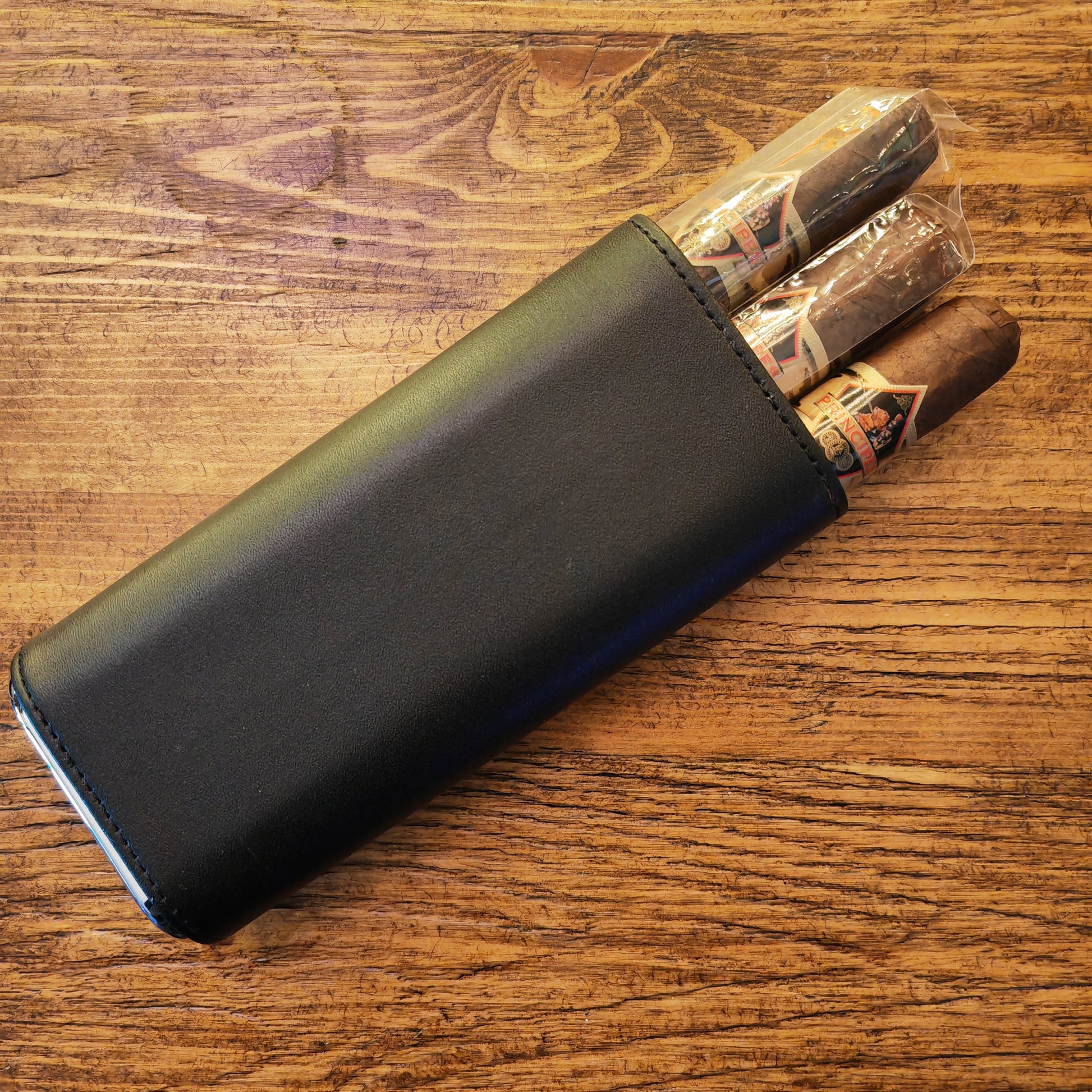 Black leather cigar case with cigars on a wooden surface