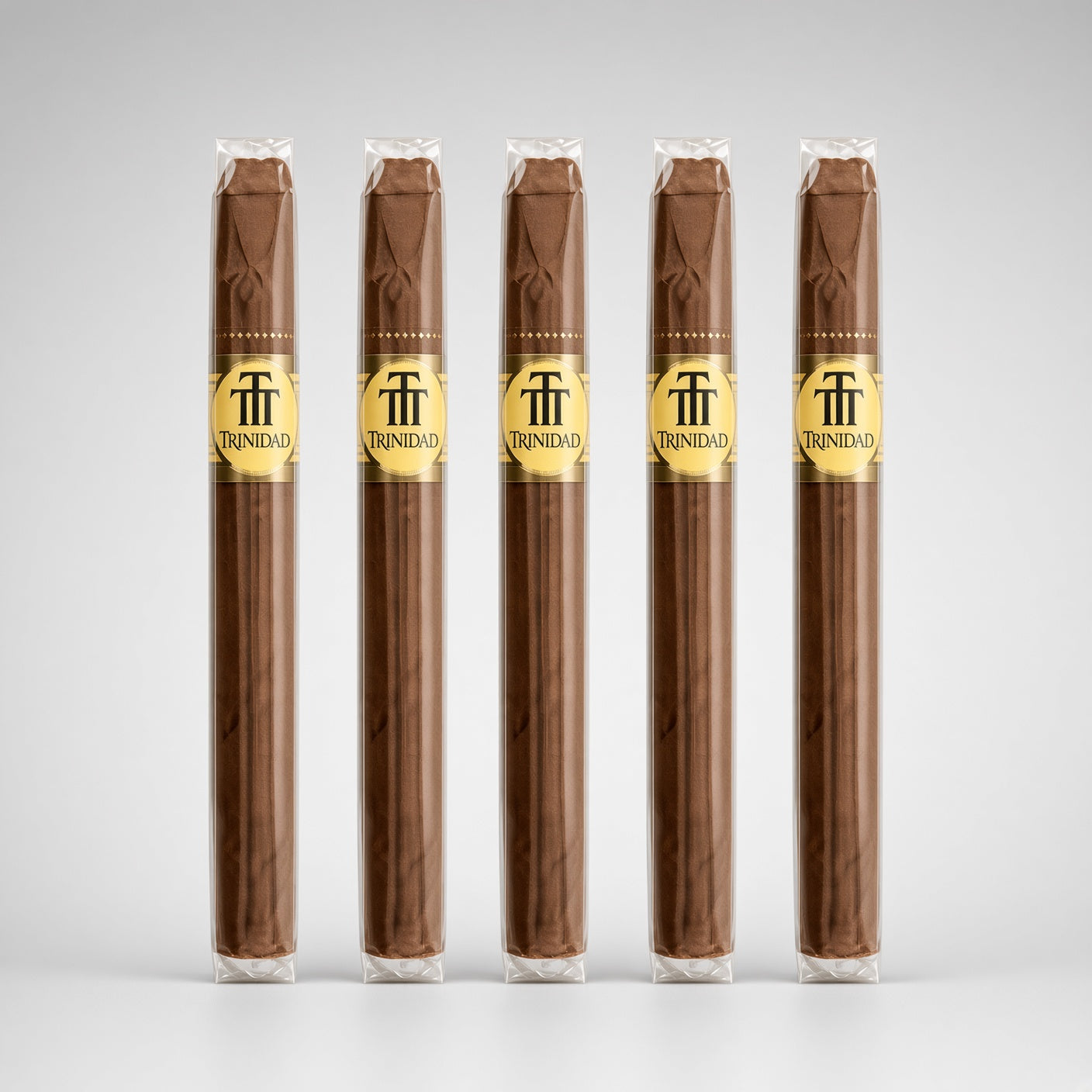 Five Trinidad cigars in clear plastic wrappers with gold bands, arranged in a row against a light gray gradient background.