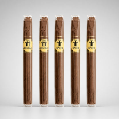 Five Trinidad cigars in clear plastic wrappers with gold bands, arranged in a row against a light gray gradient background.