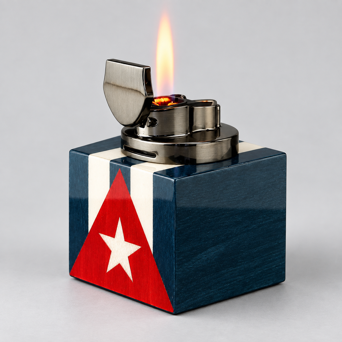 A metallic lighter with a Cuban flag design on its base, shown with a lit flame against a neutral gray background.