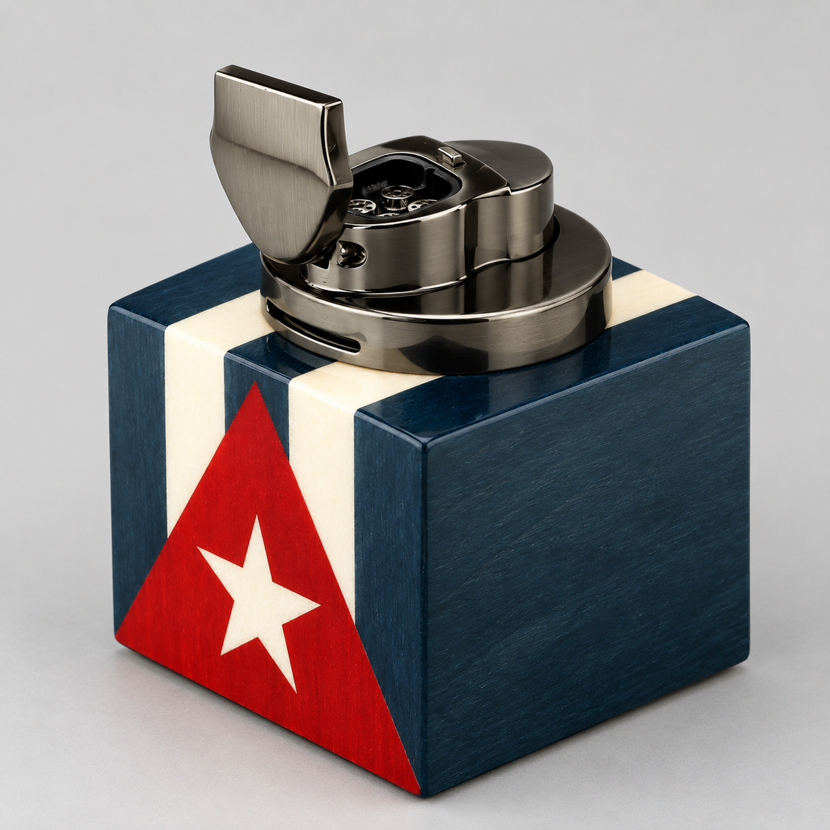 A metallic lighter with a Cuban flag-themed base, photographed on a neutral gray background.