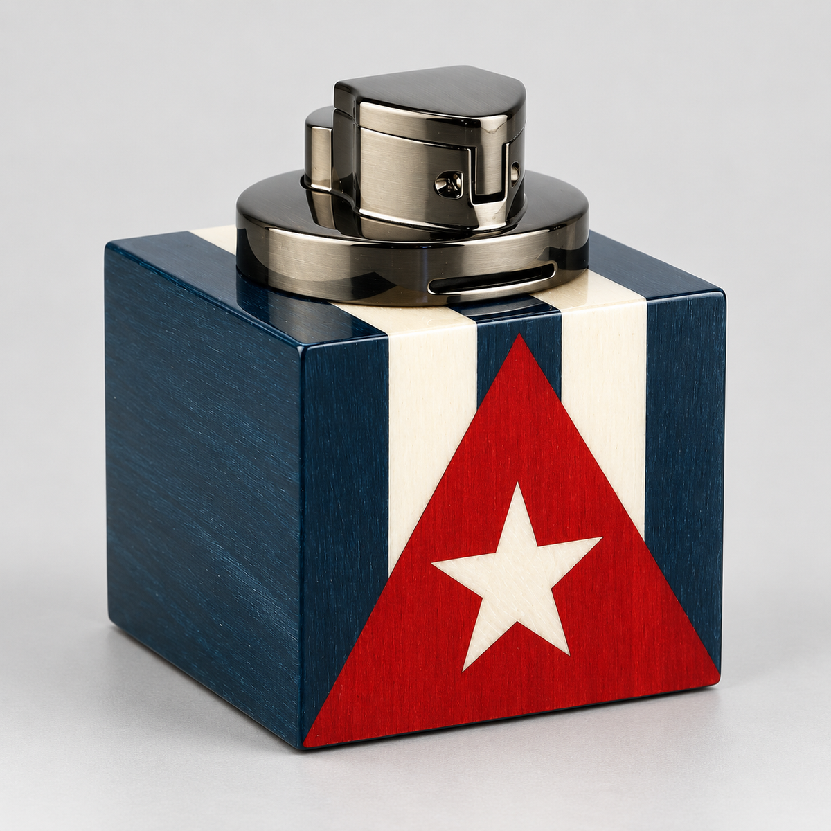 A square wooden box with a Cuban flag design, featuring dark blue and white vertical stripes with a red triangle and white star on the front. The box is topped with a metallic silver and black device, photographed on a neutral light gray background.