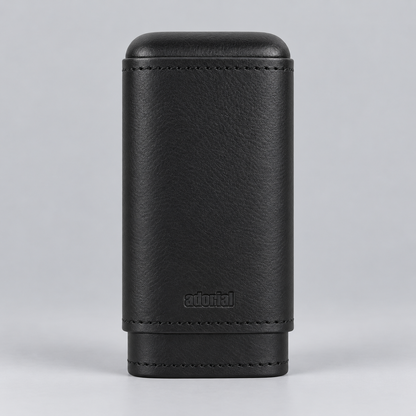 A black textured leather cigar case with stitched edges and a debossed 'adorial' logo, shown on a neutral gray background.