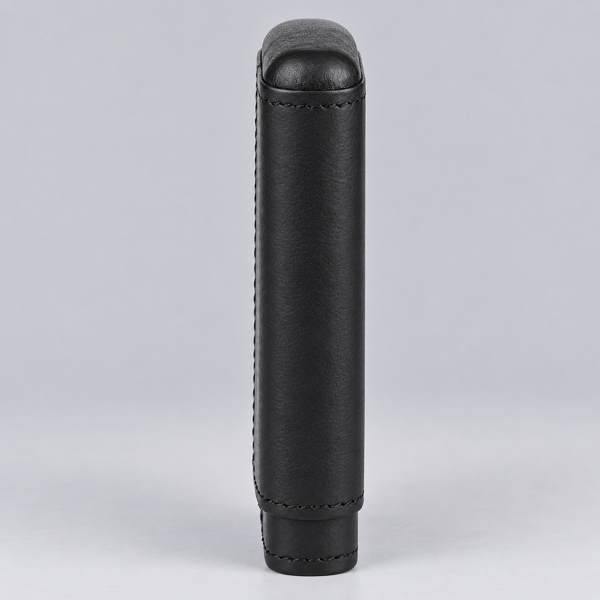 A black leather cylindrical sleeve or cover with visible stitching, standing upright against a light gray studio background.