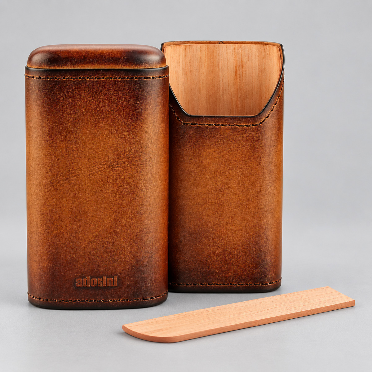 A brown leather case with a matching wooden insert and a small wooden tool, photographed on a light gray studio background. The leather case has visible stitching, a rounded rectangular shape, and the brand name 'arionil' embossed near the bottom.