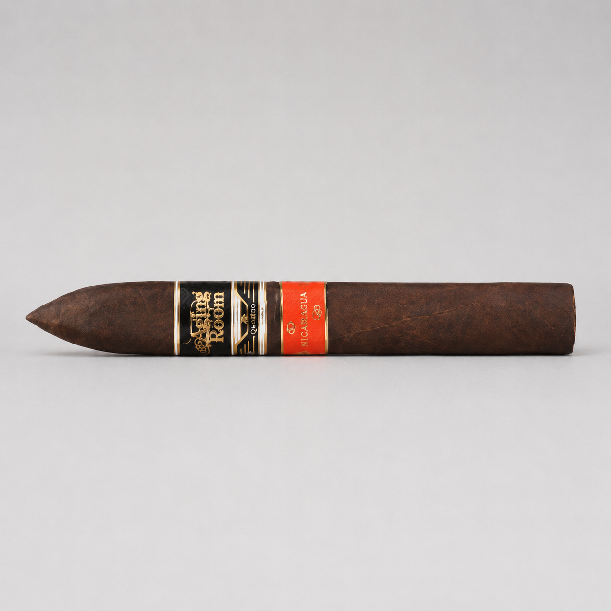 A single dark brown cigar with a black and gold band reading 'Cigar Room' and a red band, photographed horizontally against a light gray background.