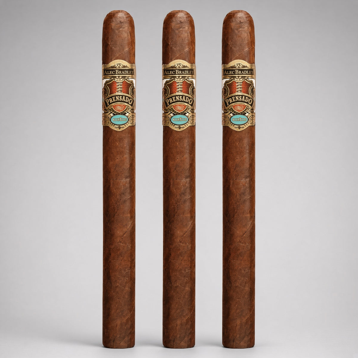 Three tall, slender cigars standing upright against a light gray studio background. Each cigar has a warm medium-brown wrapper and a decorative band near the top featuring the brand name 'Luis Alvarez' and the product name 'Premiado'.