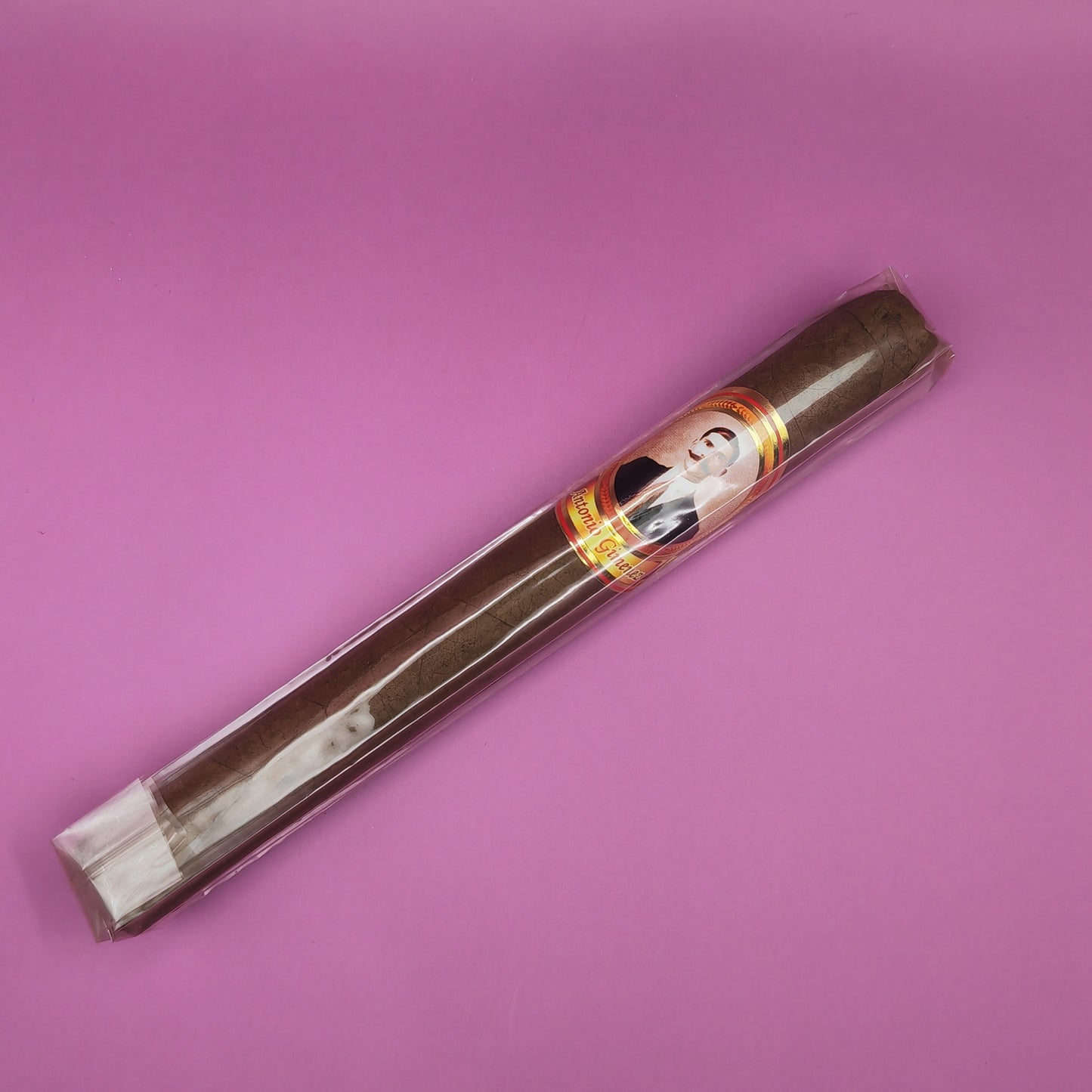 Cigar with a decorative band on a pink background