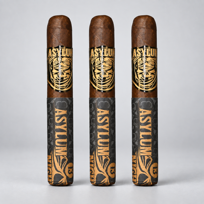 Three cigars standing upright in a row on a light gray background. Each cigar has a dark brown wrapper top with a gold and white skull logo reading 'ASYLUM', and a dark gray patterned band with vertical 'ASYLUM' text and gold decorative graphics.
