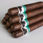 A stack of dark brown cigars with white paper bands featuring a black bull graphic and teal accents, photographed on a light gray background.