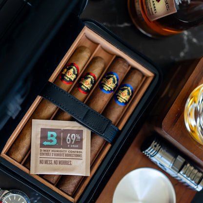Cigar humidor with cigars, a bottle of bourbon, and a glass on a wooden table.