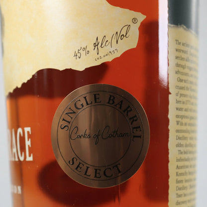 Close-up of a whisky bottle label showing a bronze circular seal that reads 'Single Barrel Corks of Cotham' over amber liquid, with part of a beige label and white text visible.