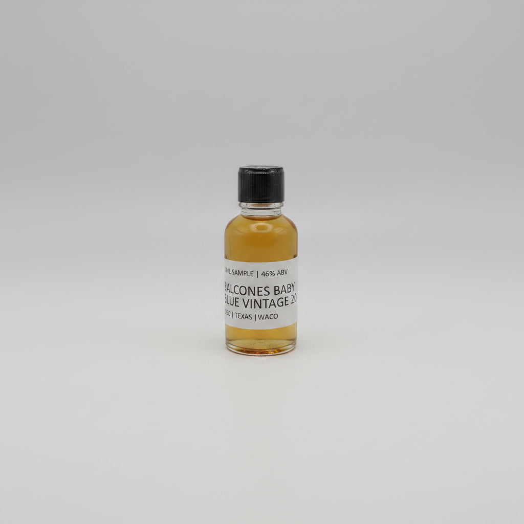 Small bottle of Balcones baby blue with a black cap and white label on a white background