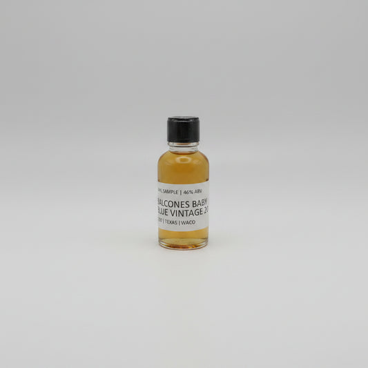 Small bottle of Balcones baby blue with a black cap and white label on a white background