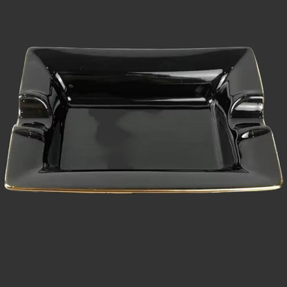 Black square cigar ashtray with gold rim on a grey background