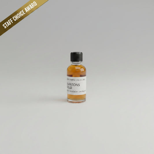 Small bottle of Blanton's Gold bourbon on a beige background