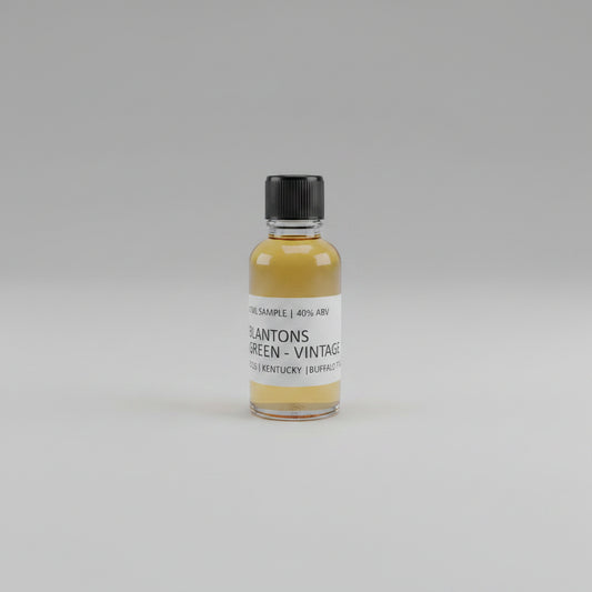 Small bottle of Blanton's Green Vintage whiskey sample on a beige background