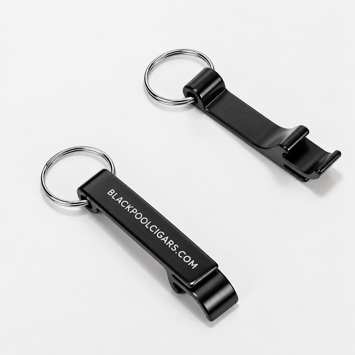 Two black metal keychain bottle openers with silver split rings, one showing the white printed text 'BLACKPOOL.CIGARS.