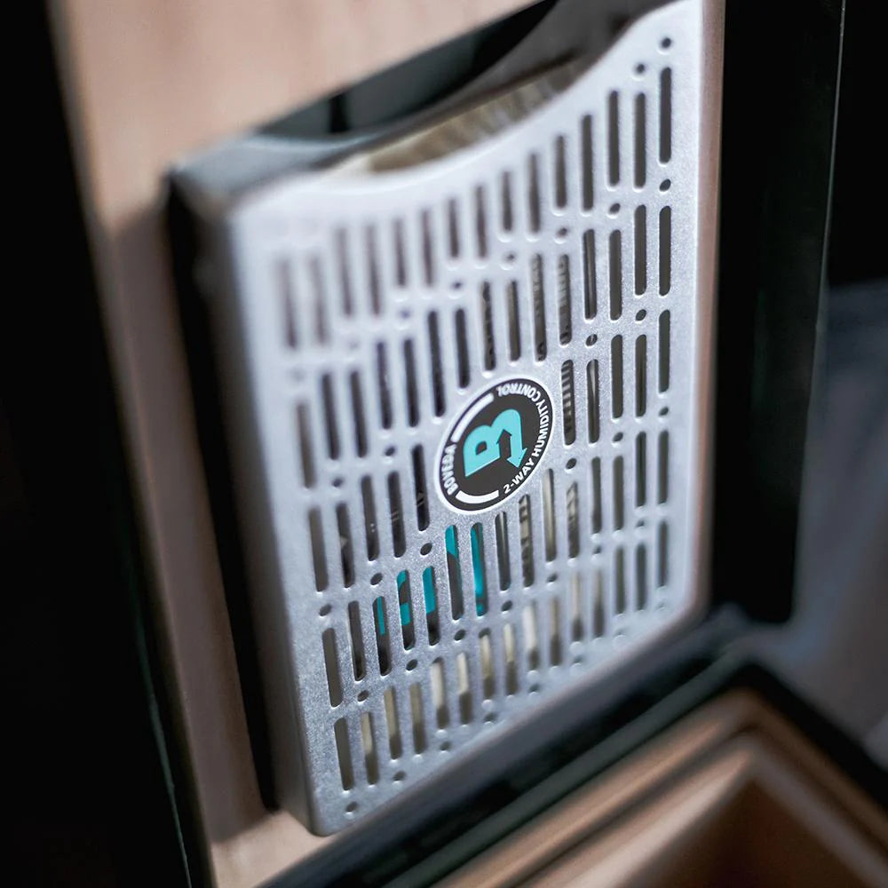 Close-up of a Boveda metal bracket device with a grid pattern and a Boveda logo on a wooden surface