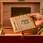 Hand holding a Boveda humidity control pack over an open wooden humidor.