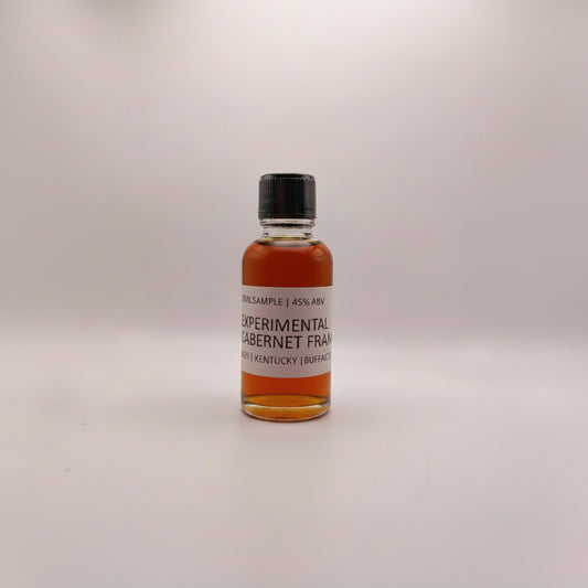 Small bottle of whiskey with a label on a white surface