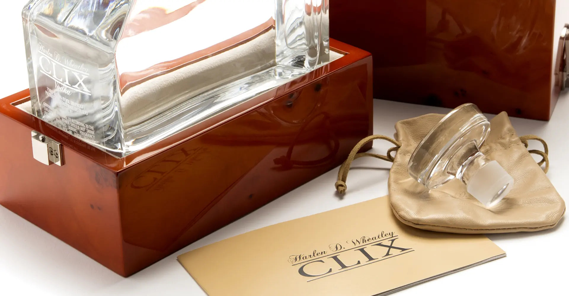Clear glass bottles with wooden box and branded paper on a white surface