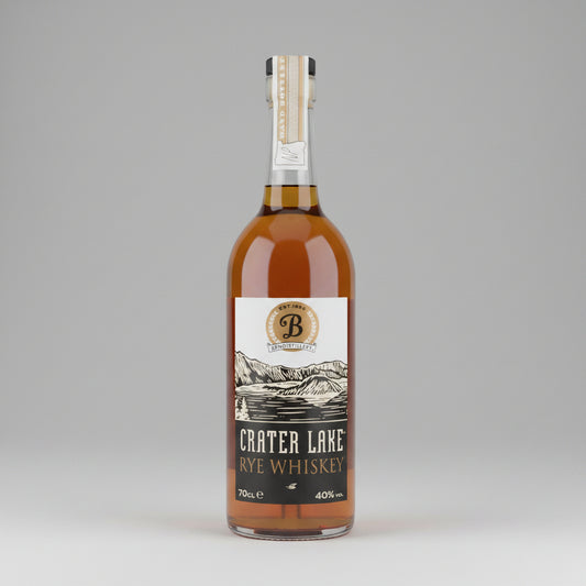 A bottle of Crater Lake Handcrafted American Rye Whiskey, showing the amber liquid inside a clear glass bottle with a white and black label.