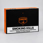Camacho cigar packaging box in black and orange with a prominent white warning label reading 'SMOKING KILLS' and health text, photographed on a light gray background.