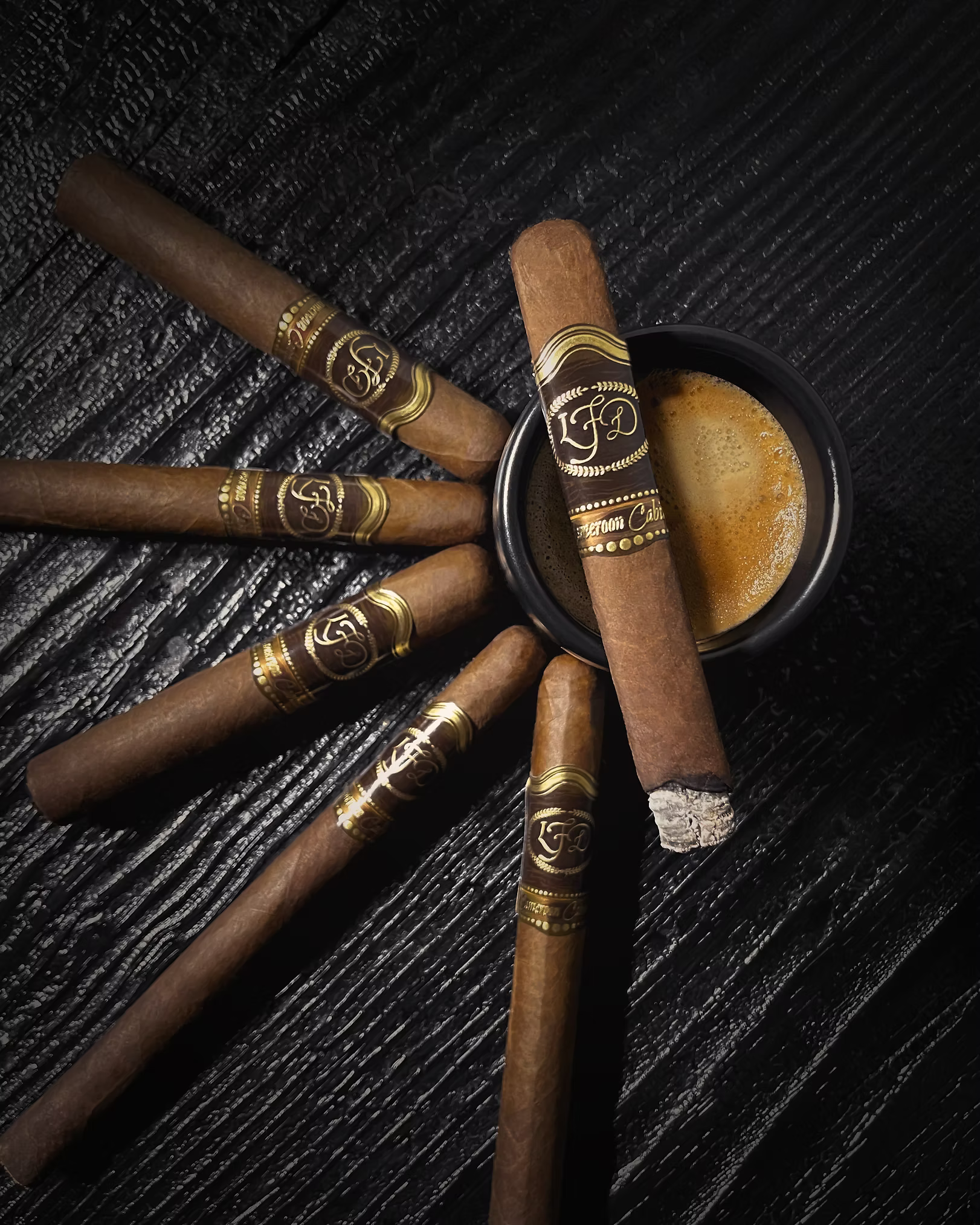 Cigars with gold bands arranged on a textured dark surface