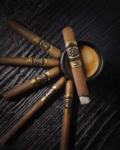 Cigars with gold bands arranged on a textured dark surface