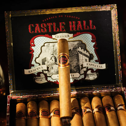 Open box of Castle Hall cigars with a single cigar sticking out, surrounded by dark background.