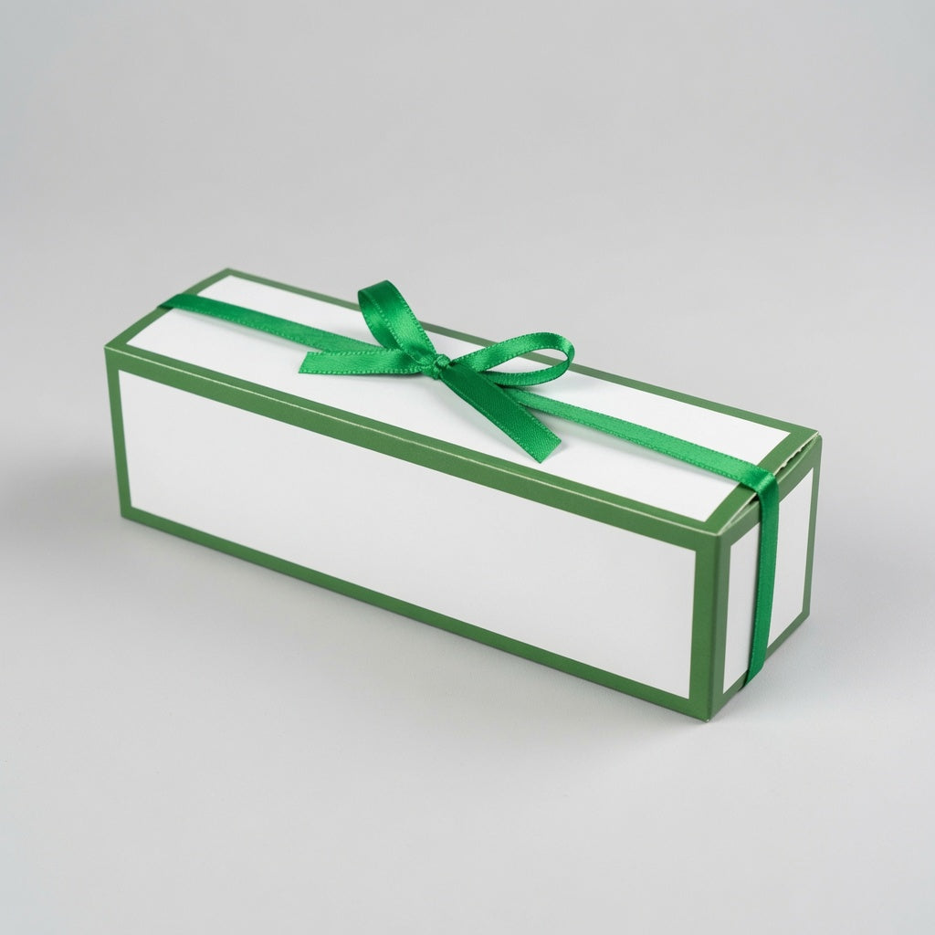 A rectangular white gift box with green borders and a green ribbon tied in a bow on top, photographed on a light gray studio background.