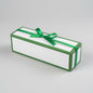 A rectangular white gift box with green borders and a green ribbon tied in a bow on top, photographed on a light gray studio background.