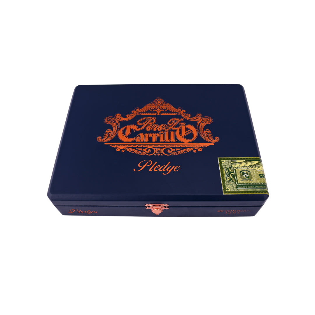 A dark blue cigar box for 'Paso La Carrililla Pledge' featuring ornate orange lettering and a small green and white postage stamp design on the front, set against a plain white background.