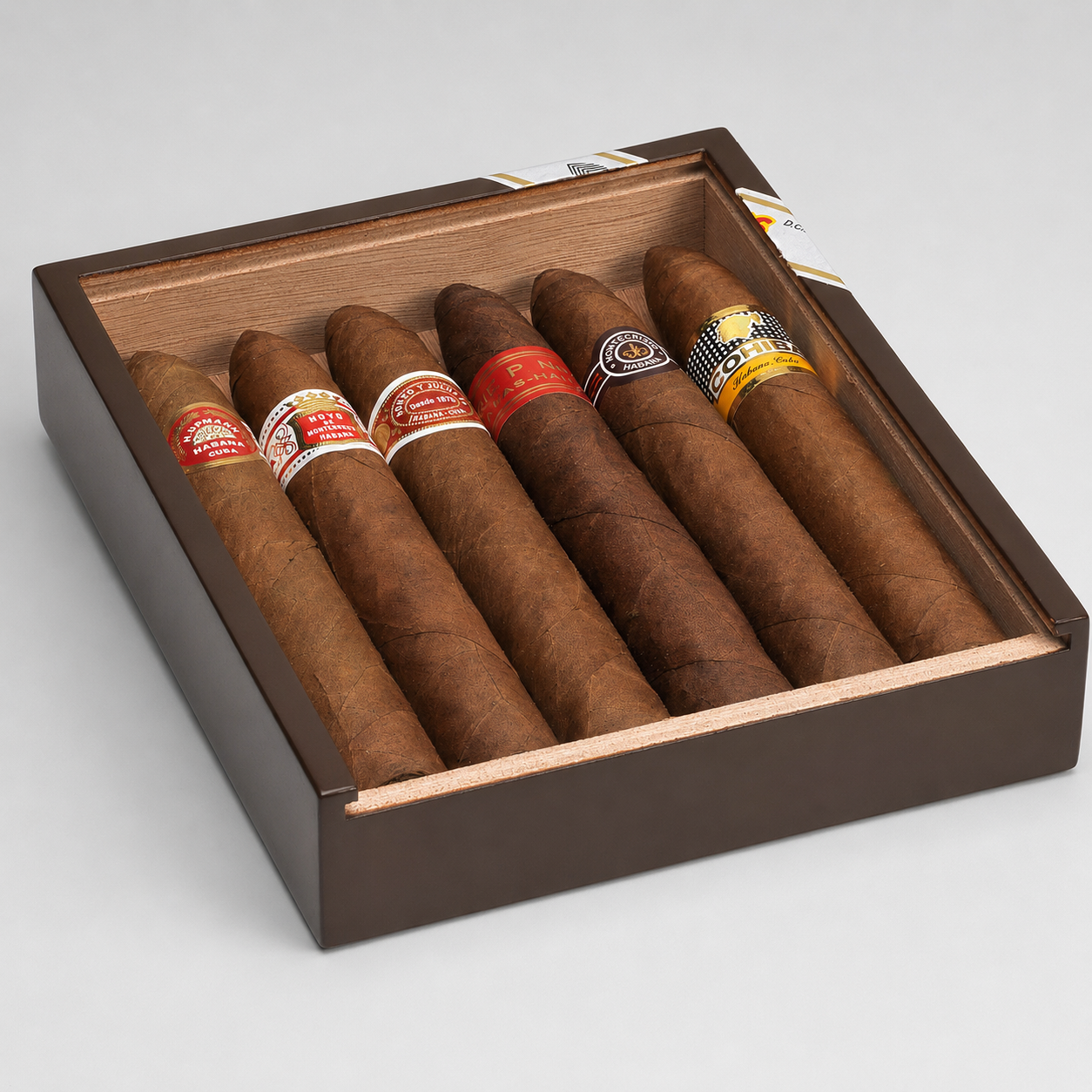 An open dark brown cigar box containing six cigars with colorful bands, photographed on a light gray studio background.